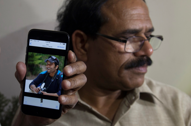 A man holds up a smartphone photo of Alok Madasani, an engineer who was injured in the shooting as Madasani’s father Jaganmohan Reddy talks to the media in Hyderabad, India on Friday (AP Photo/Mahesh Kumar A.)